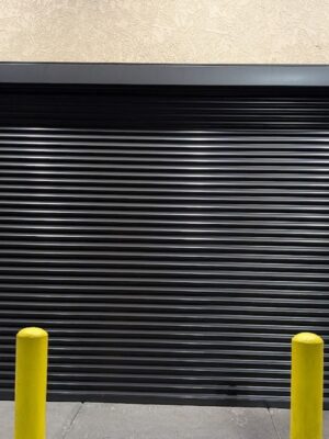 Security shutter style roll-up door with two yellow Ballards in front of it