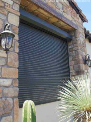 A black Security shutter style roll-up door installed on a home with rock exterior